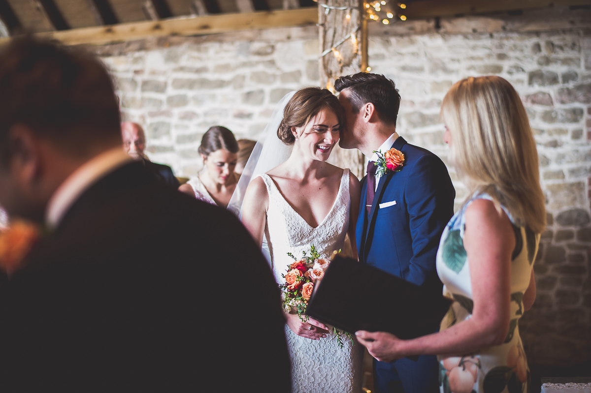 A bride and groom share a romantic kiss captured by their wedding photographer.