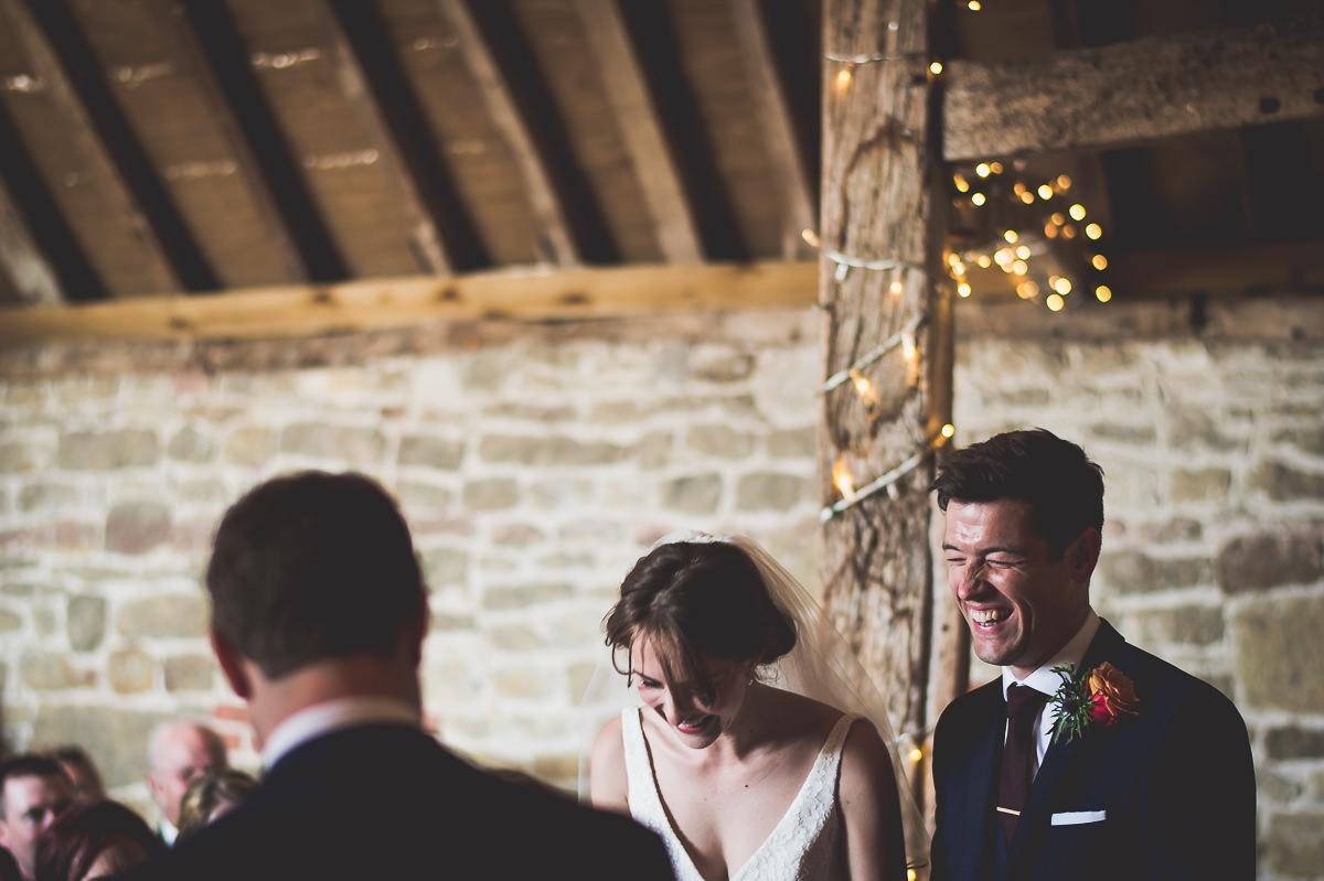 A wedding photographer captures a laughing bride and groom during their ceremony.