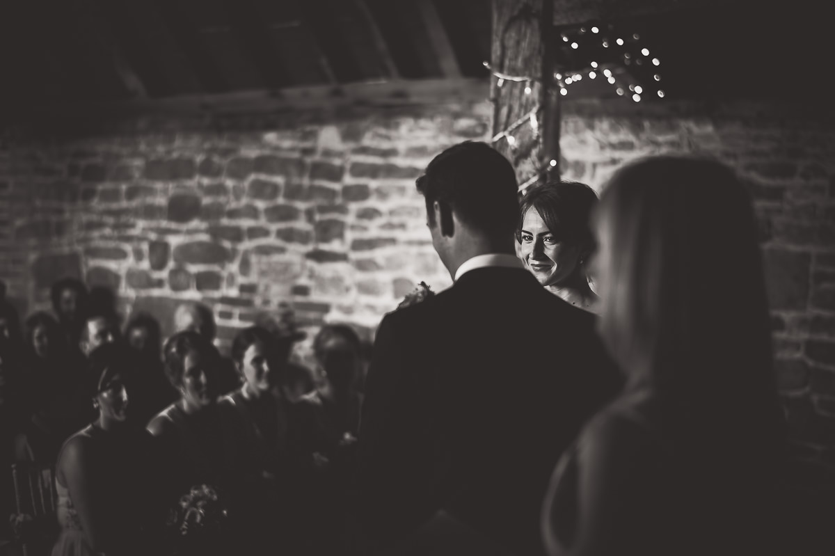 A black and white wedding photo of a bride and groom in a barn.