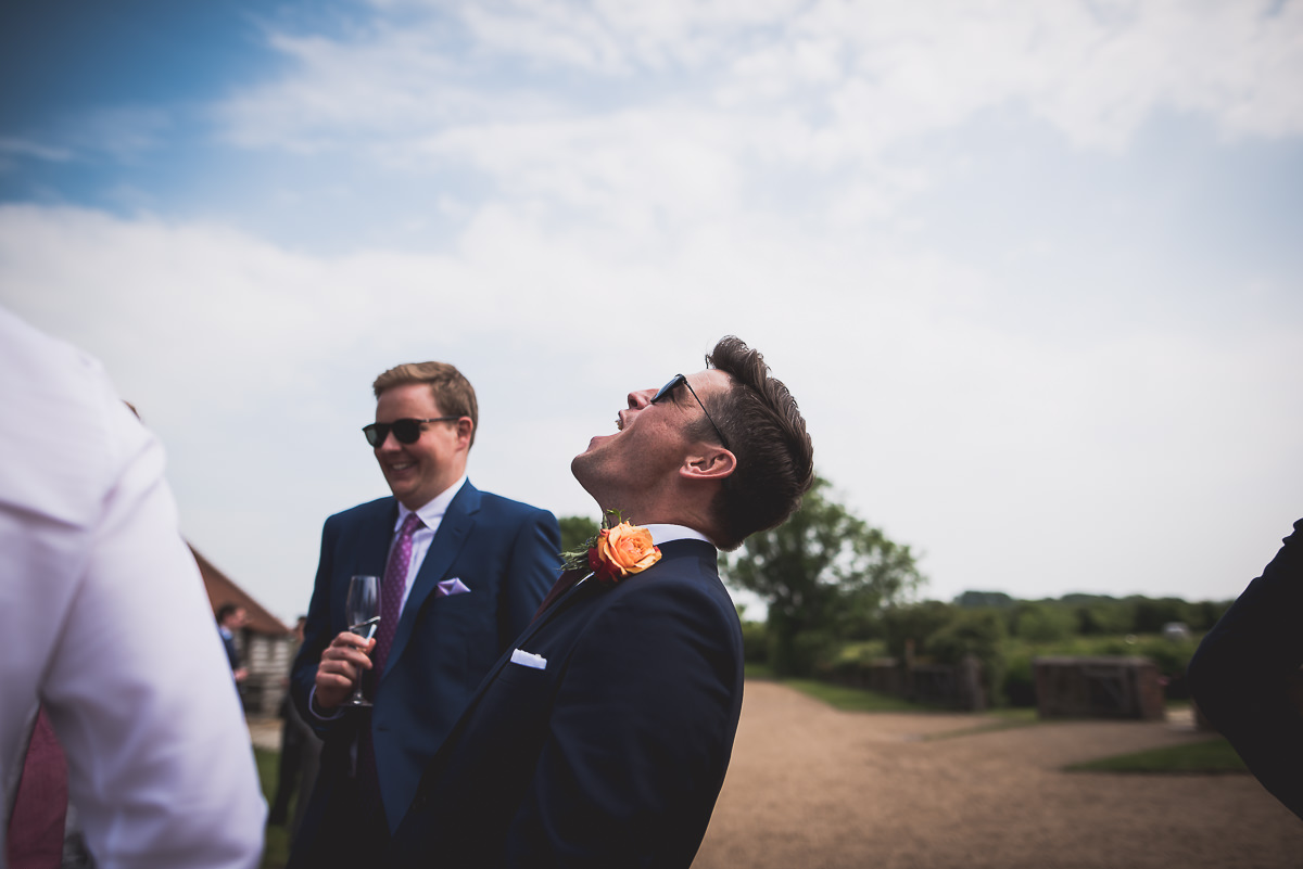 A groom, dressed in a suit, gazes up at the wedding photographer capturing their special moments.