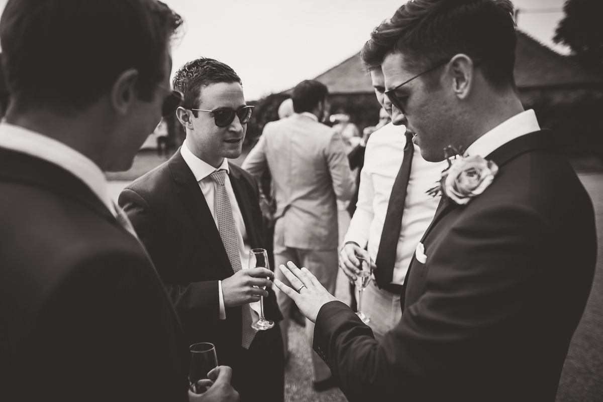 A black and white photo capturing a group of men at a wedding celebration.