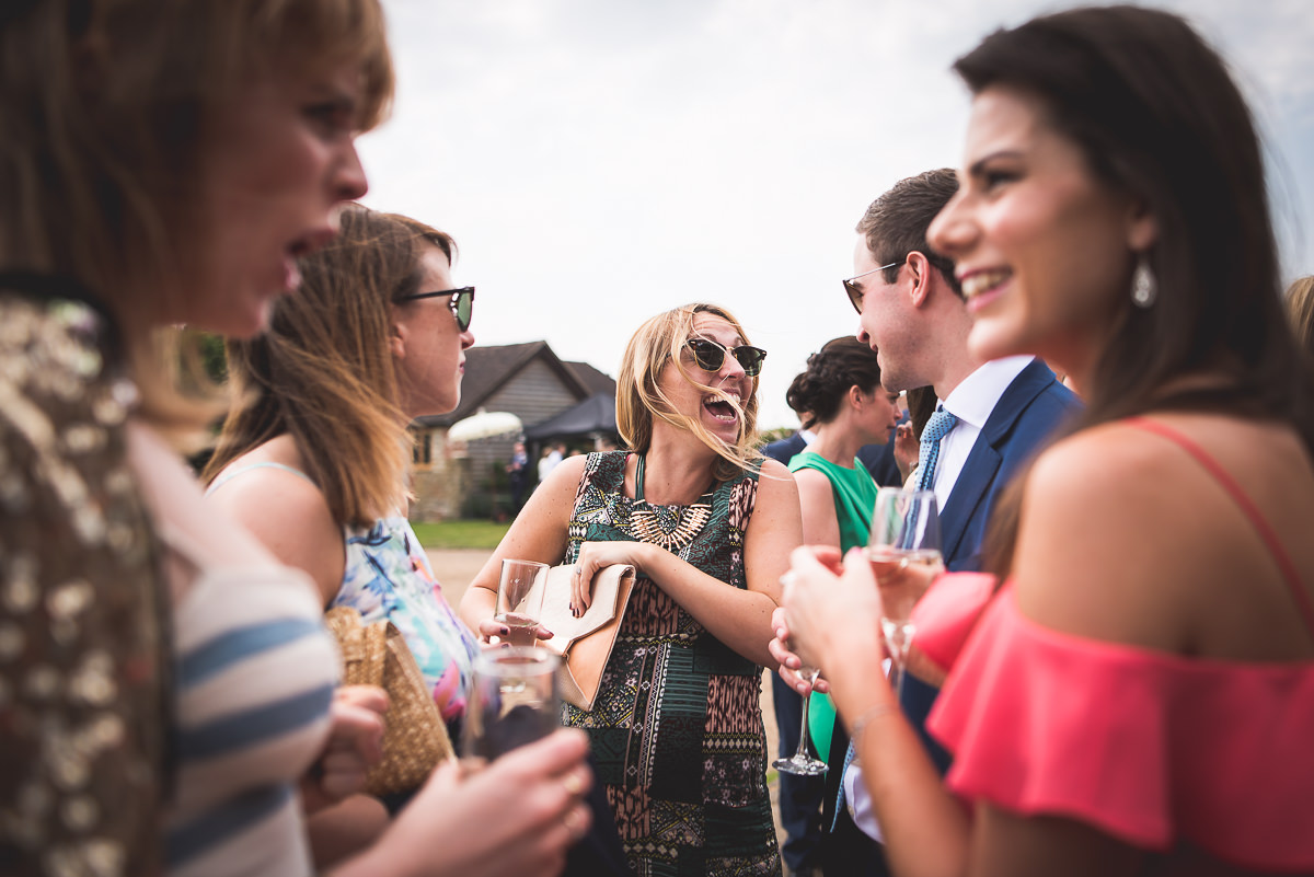 A group of people, including the groom, drinking wine at an outdoor wedding event, captured by a wedding photographer for memorable wedding photos.