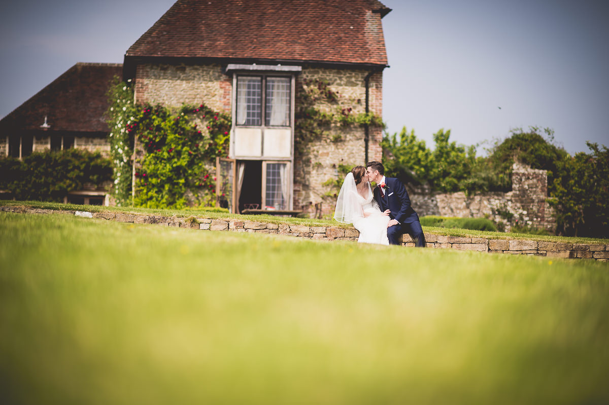 A bride and groom, captured by a wedding photographer, pose in front of an old house.