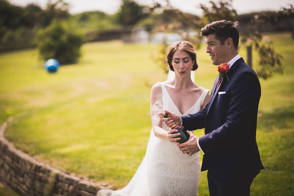 A wedding couple posing with a bottle of wine for their photos.