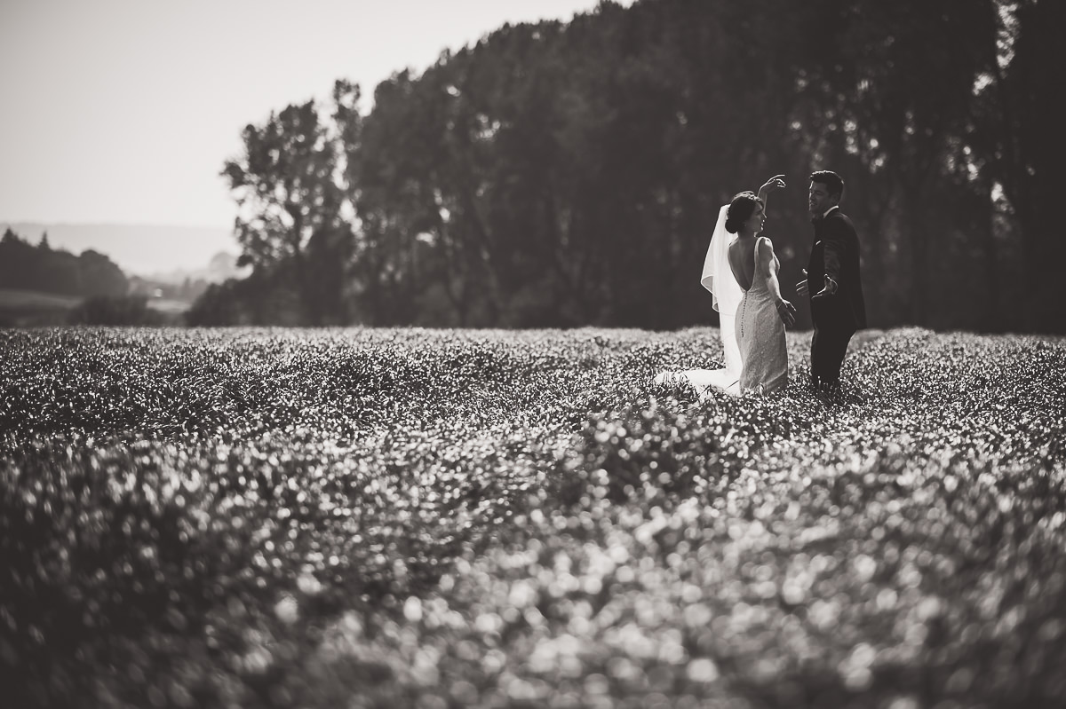 A groom posing for wedding photos in a field, captured by a wedding photographer.