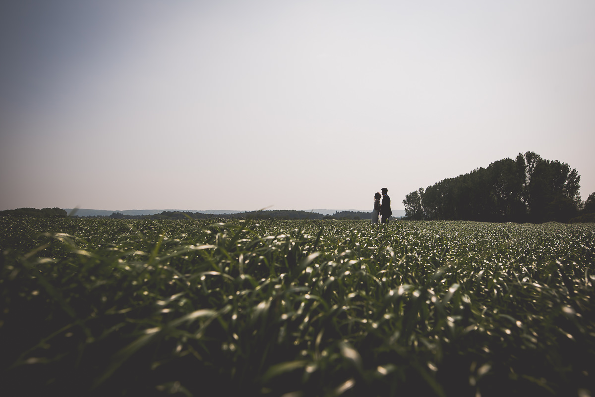 A groom standing in the middle of a field.