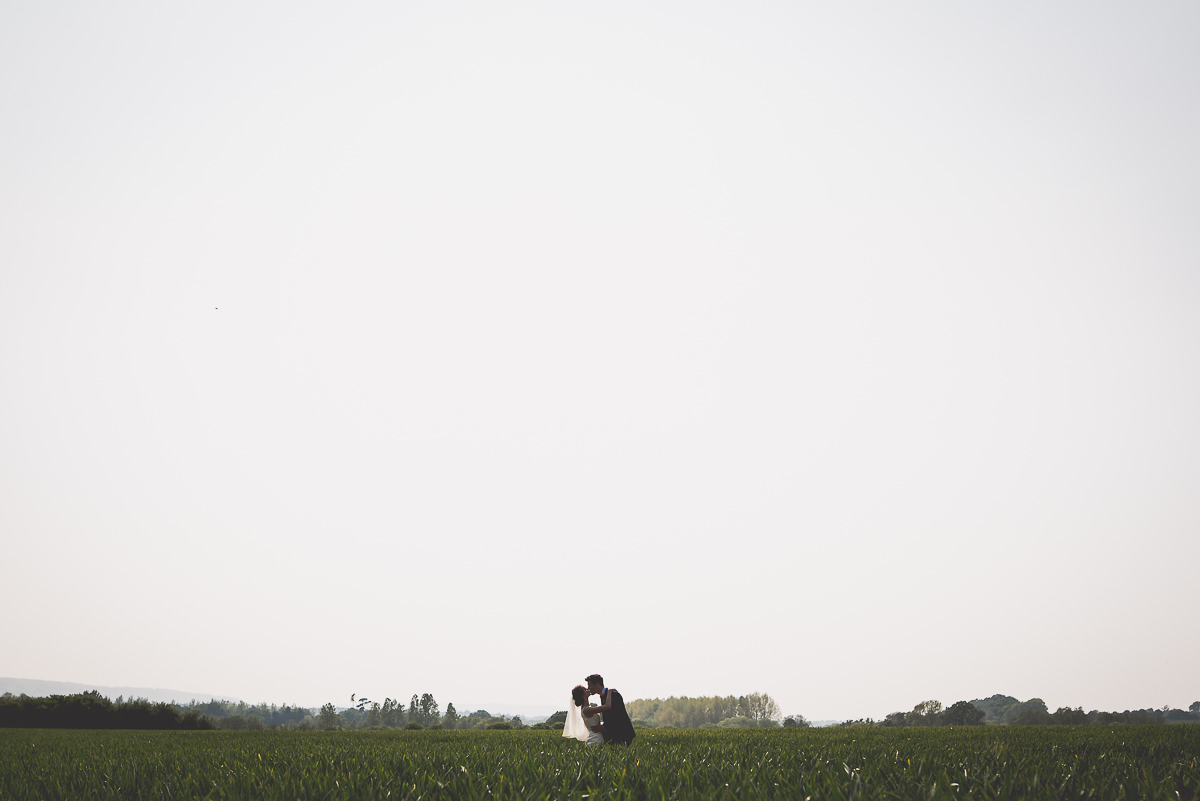 A bride and groom posing for wedding photos in a field, captured by a talented wedding photographer.