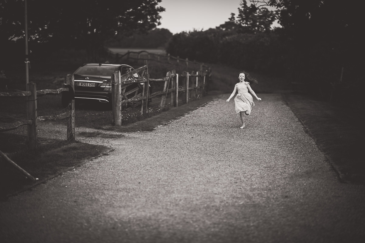 A bride in a white dress running down a path.