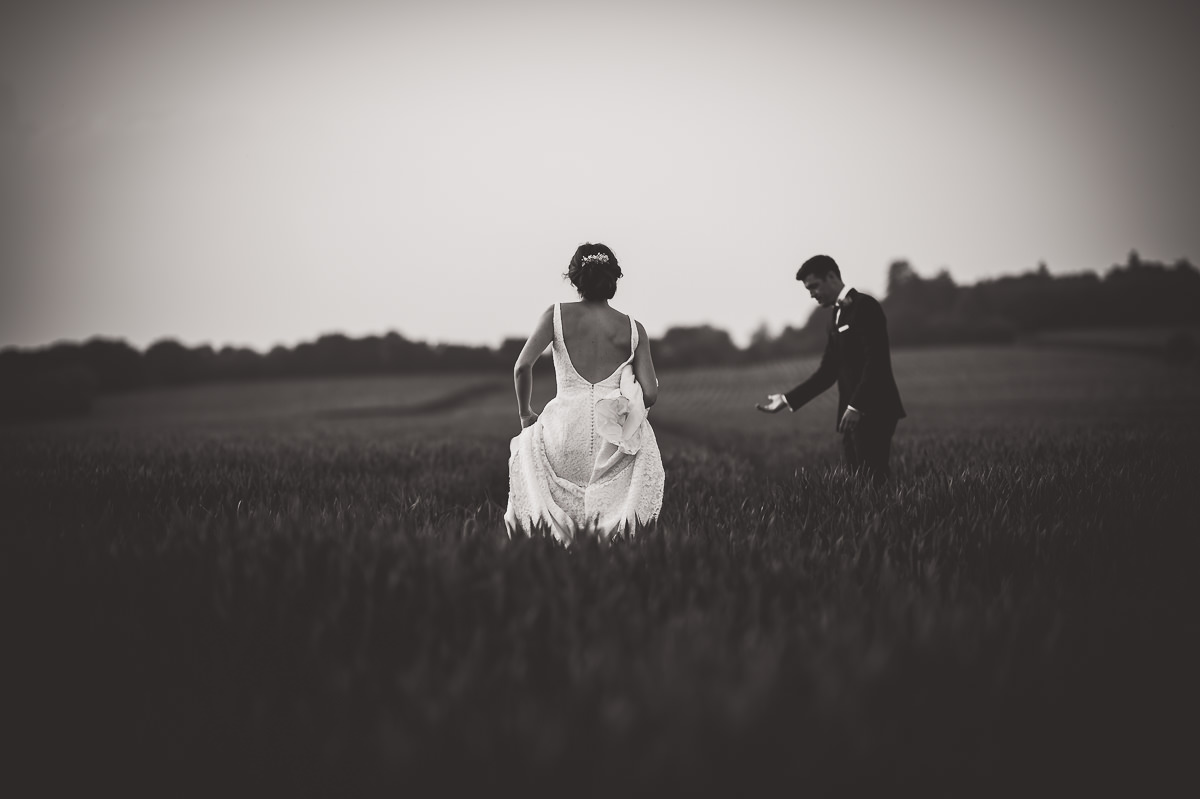 A wedding couple captured in a romantic wedding photo amid a picturesque field.