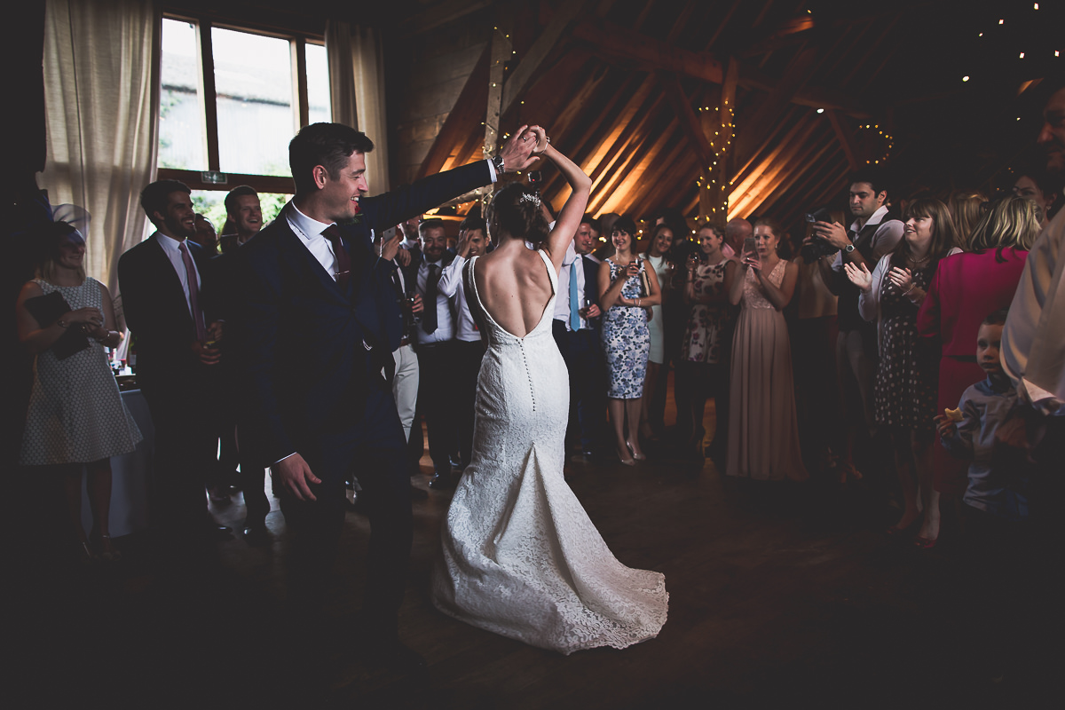 A groom and bride gracefully dancing in a rustic barn, captured by a skilled wedding photographer for a cherished wedding photo.