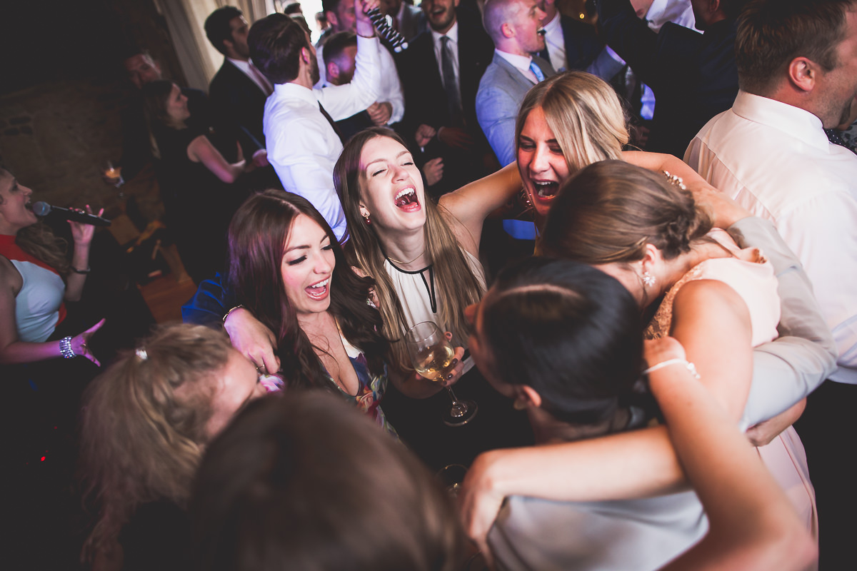 A group of people hugging at a wedding reception captured by a wedding photographer.