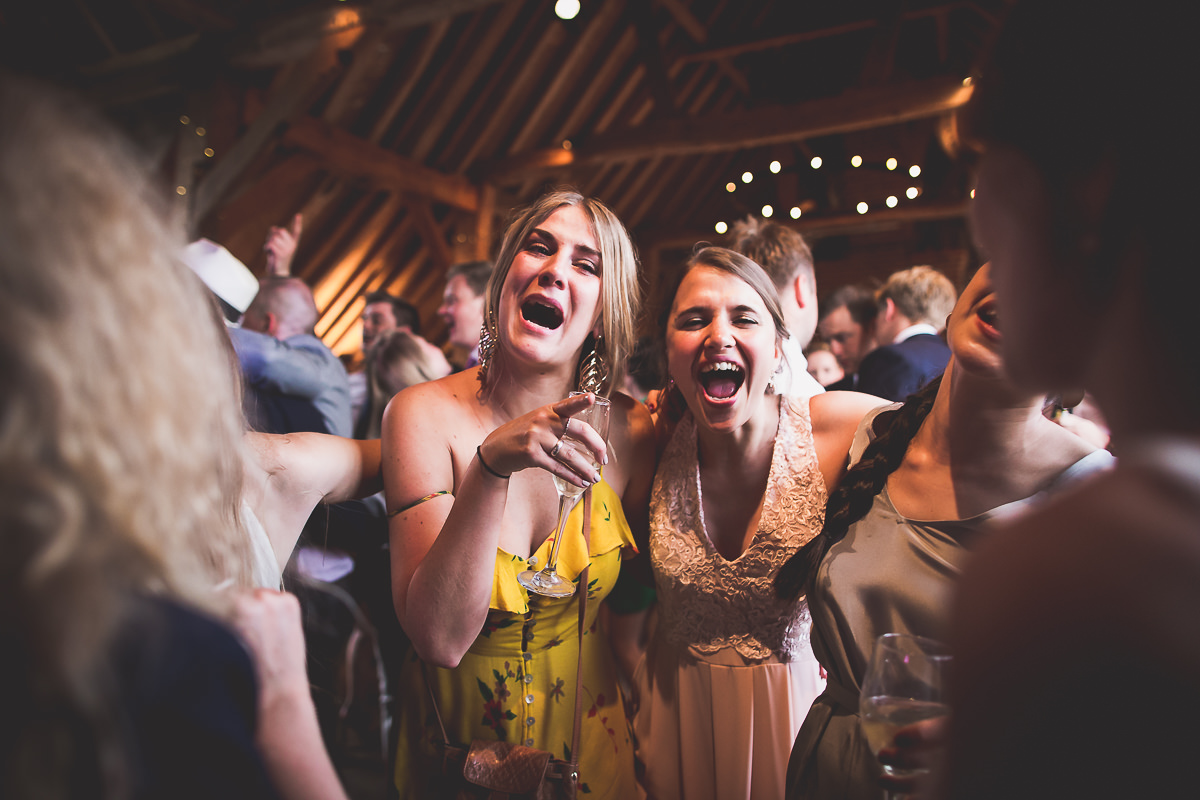 A group of bridesmaids laughing at the groom during a wedding reception.