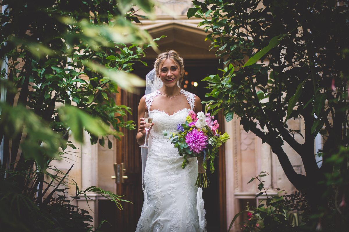 A wedding photographer captures a bride in her wedding dress as she stands in a doorway.