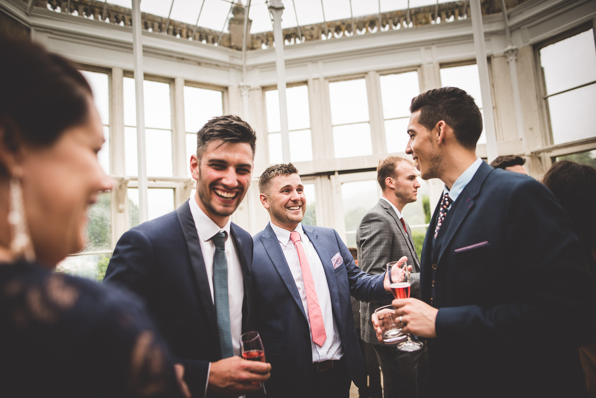 A group of men, including the groom, laughing at a wedding reception.