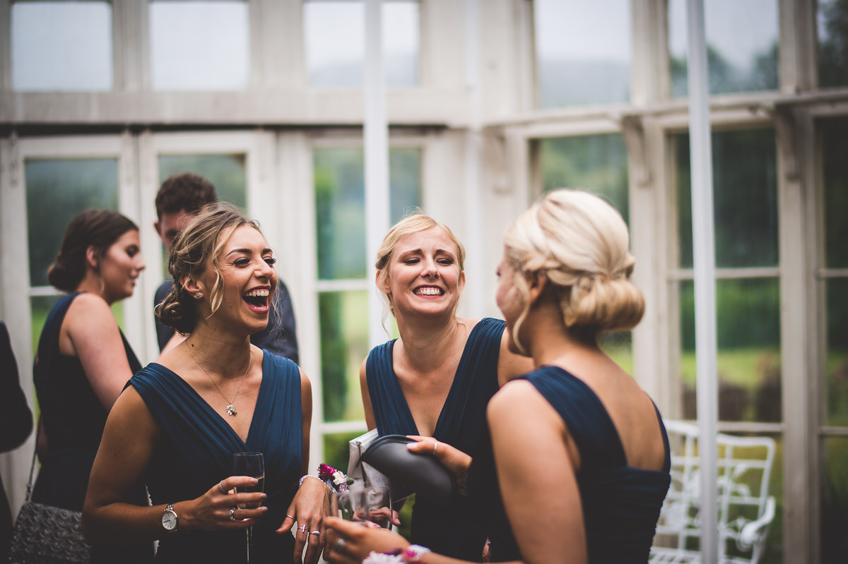 Bridesmaids in a room, laughing at each other during wedding preparations.