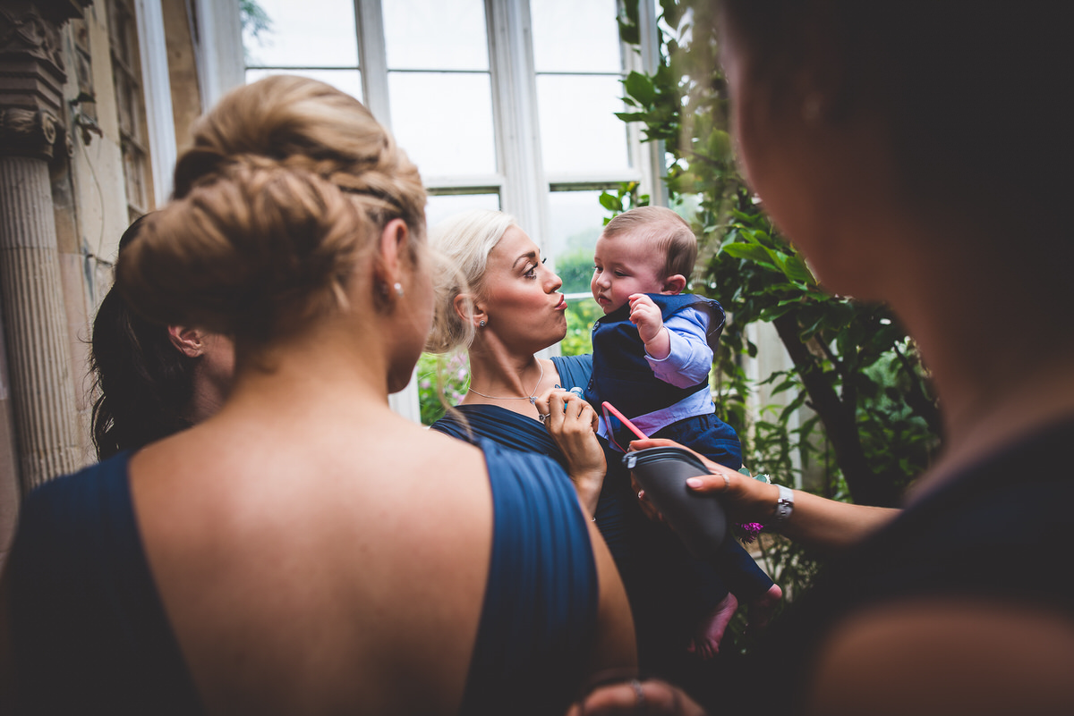 Bride and bridesmaids captivated by a baby in this heartwarming wedding photo.