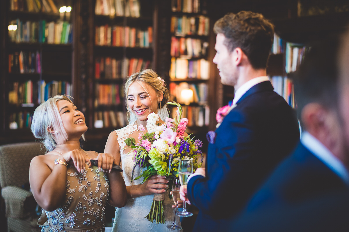 A bride and groom posing for their wedding photo in front of a bookshelf.