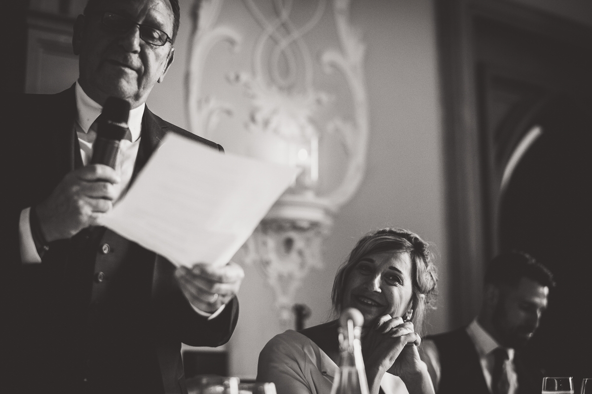 A man is giving a heartfelt speech at a wedding while the bride poses for a memorable wedding photo.