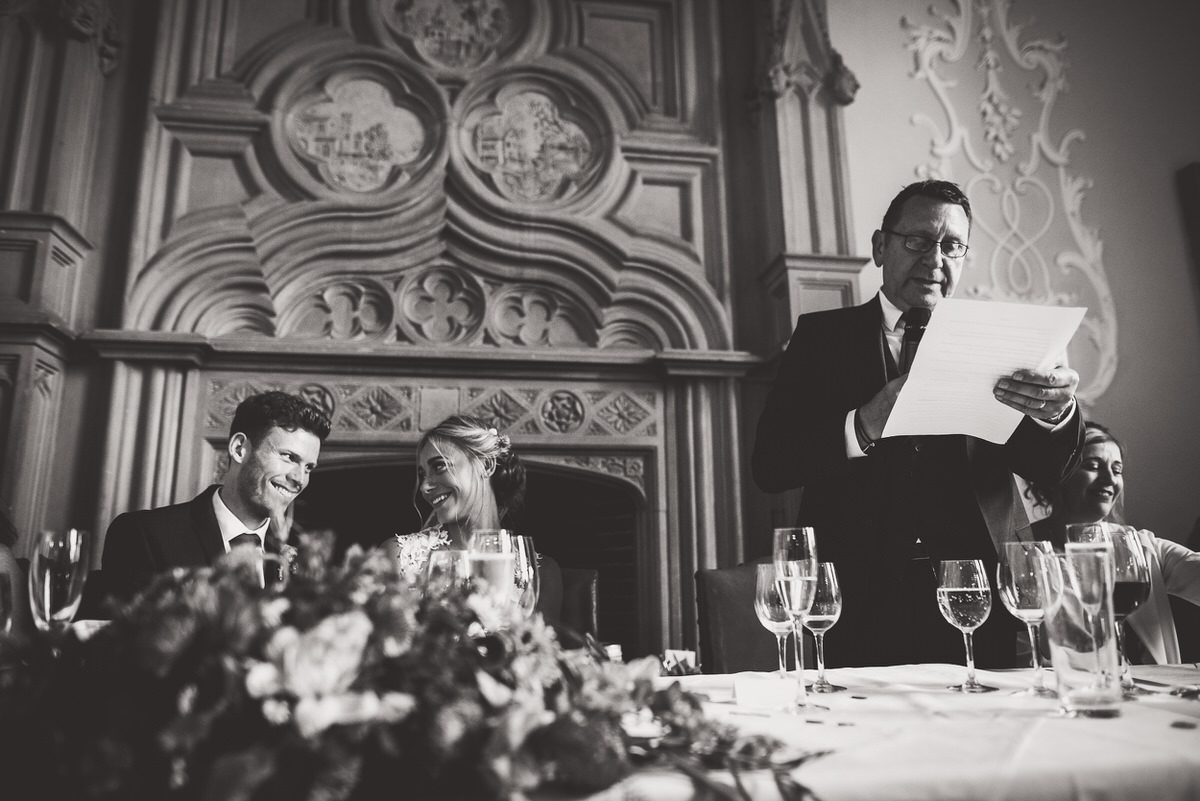 A groom reading a speech at his wedding in a black and white photo.