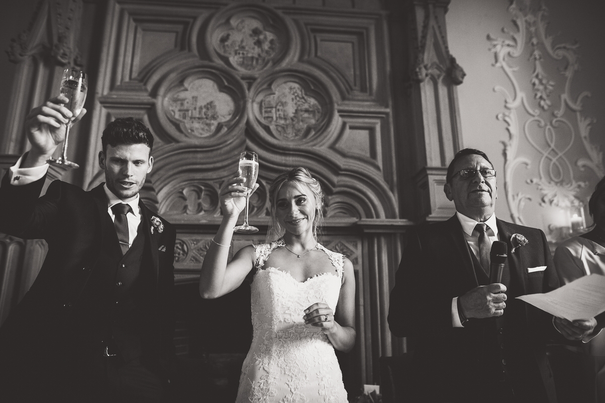 A wedding photographer captures a black and white photo of the bride and groom toasting champagne.