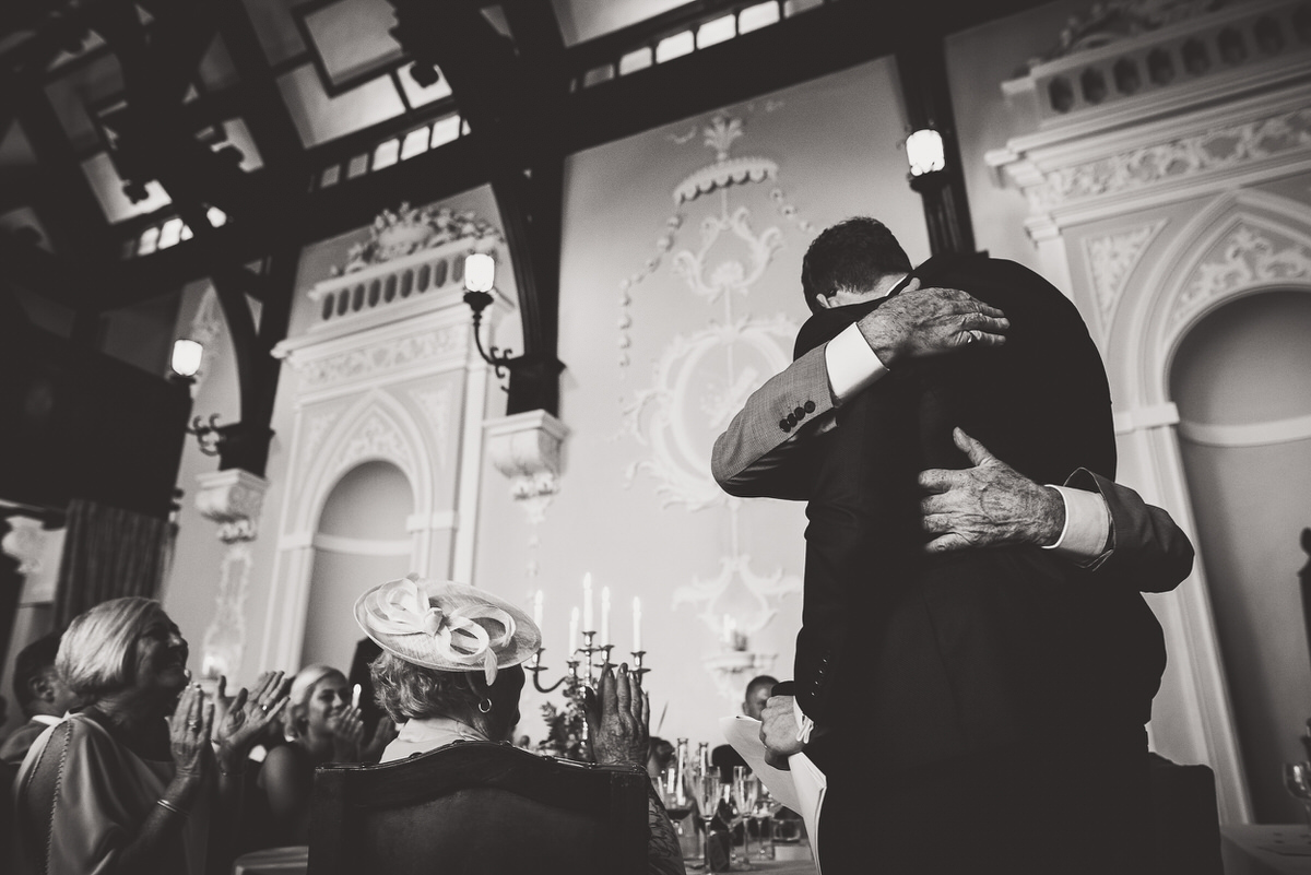 The groom is hugging another man at a wedding.