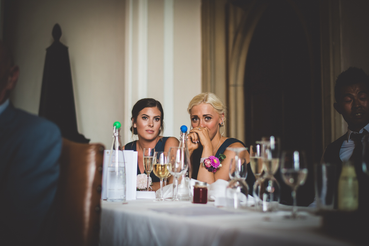 A bride and wedding guests posing for a group photo at a table with wine glasses.