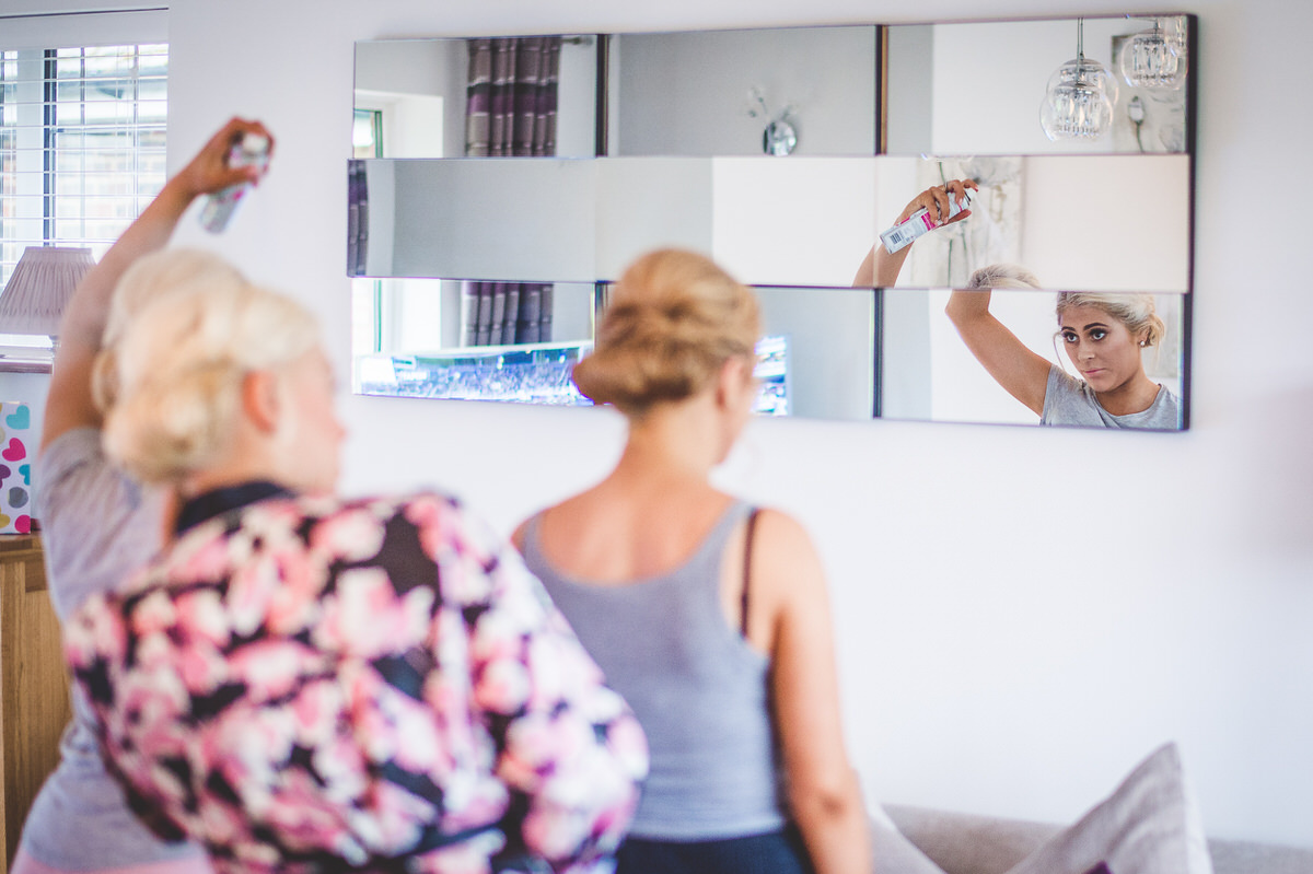 A group of women posing for a wedding photo in front of a mirror.