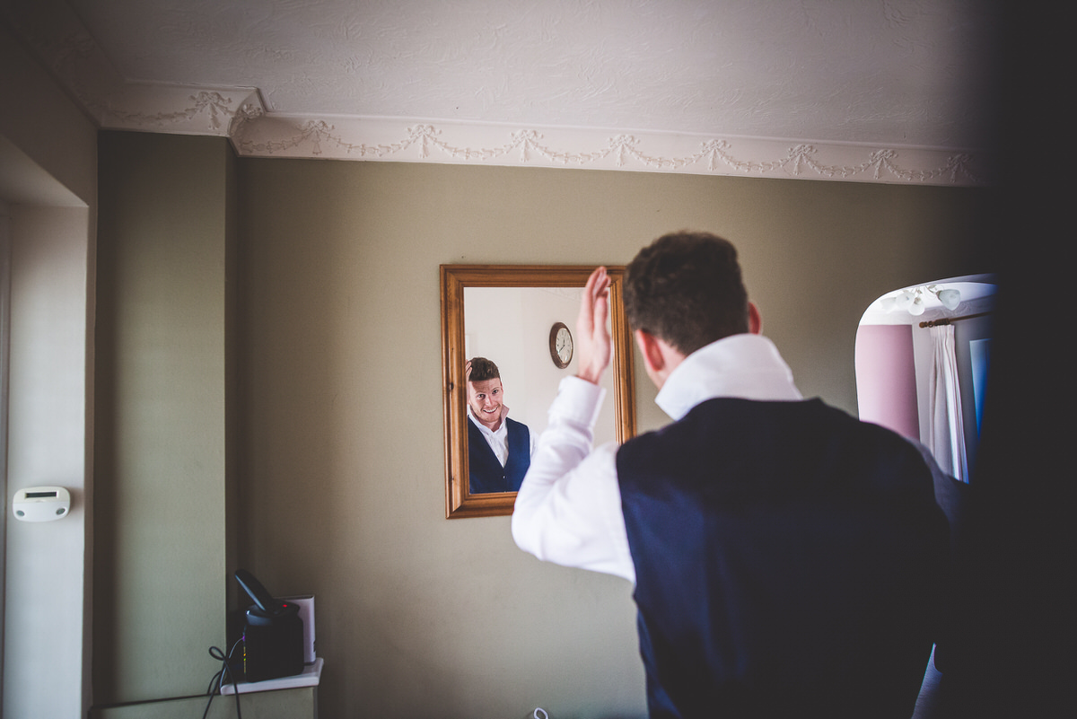 A groom putting on his tie for his wedding photo.