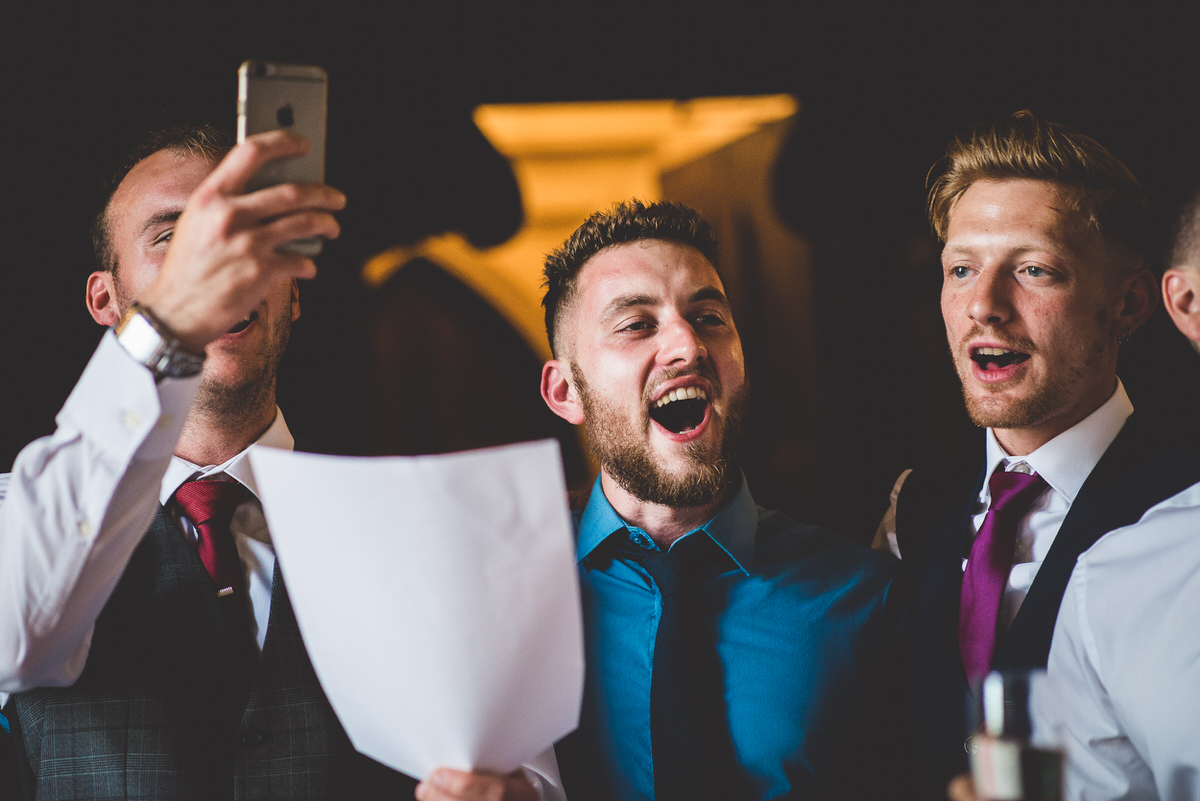 A group of men are laughing while posing for a wedding photo.