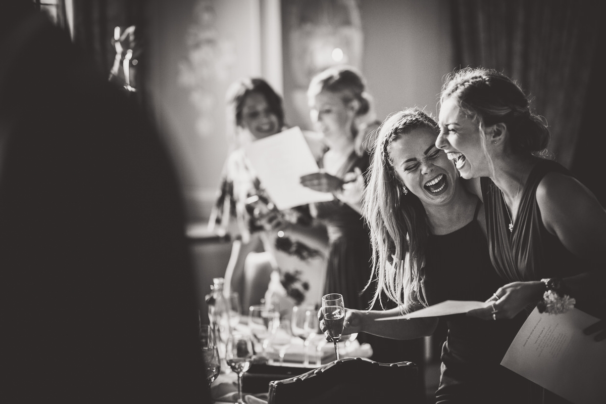 A black and white wedding photo capturing a joyful group of women laughing.