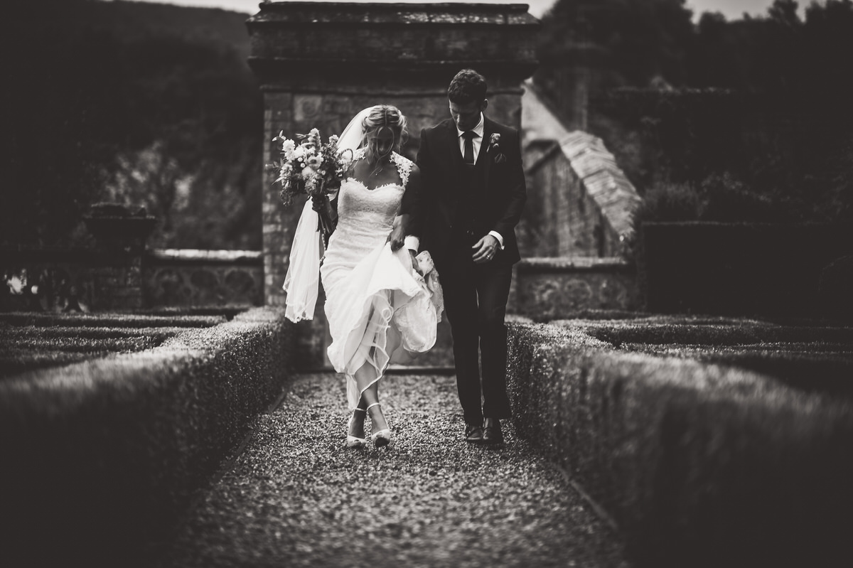 A bride and groom captured beautifully by a wedding photographer, strolling along a path in classic black and white.