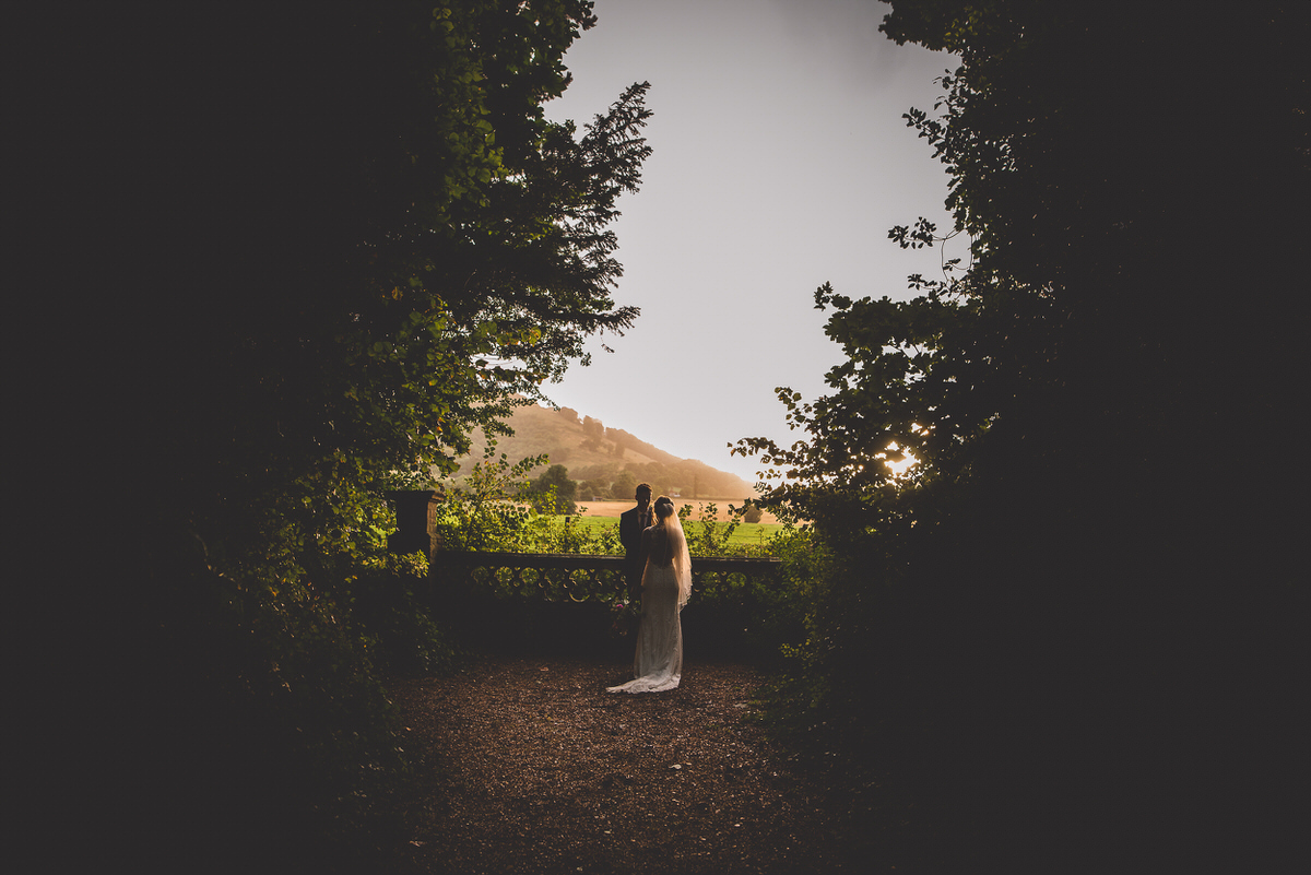A wedding photographer captures a groom and bride amidst the trees.