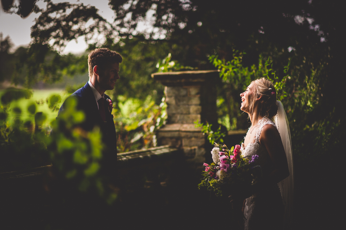 A wedding photographer captures the groom mesmerized by his bride in a dim lit ceremony.