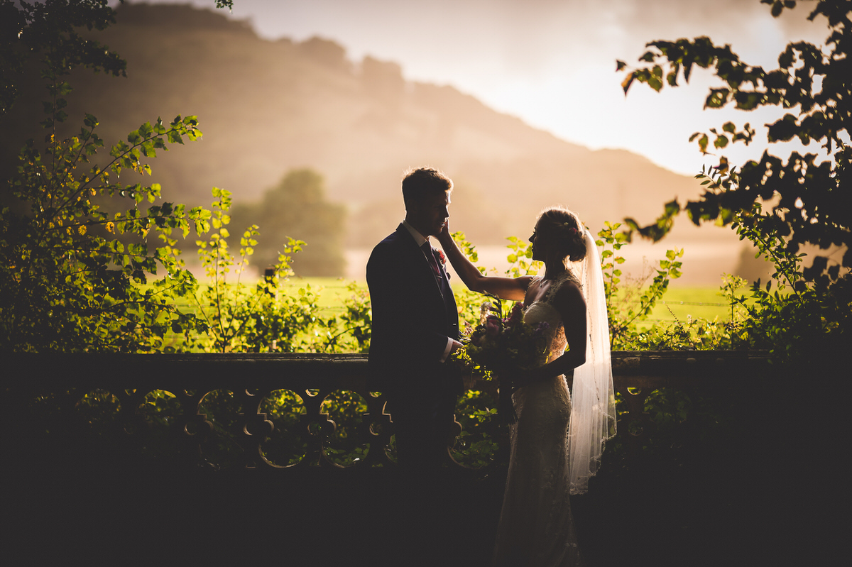 A bride and groom are silhouetted in front of a tree in their wedding photo.