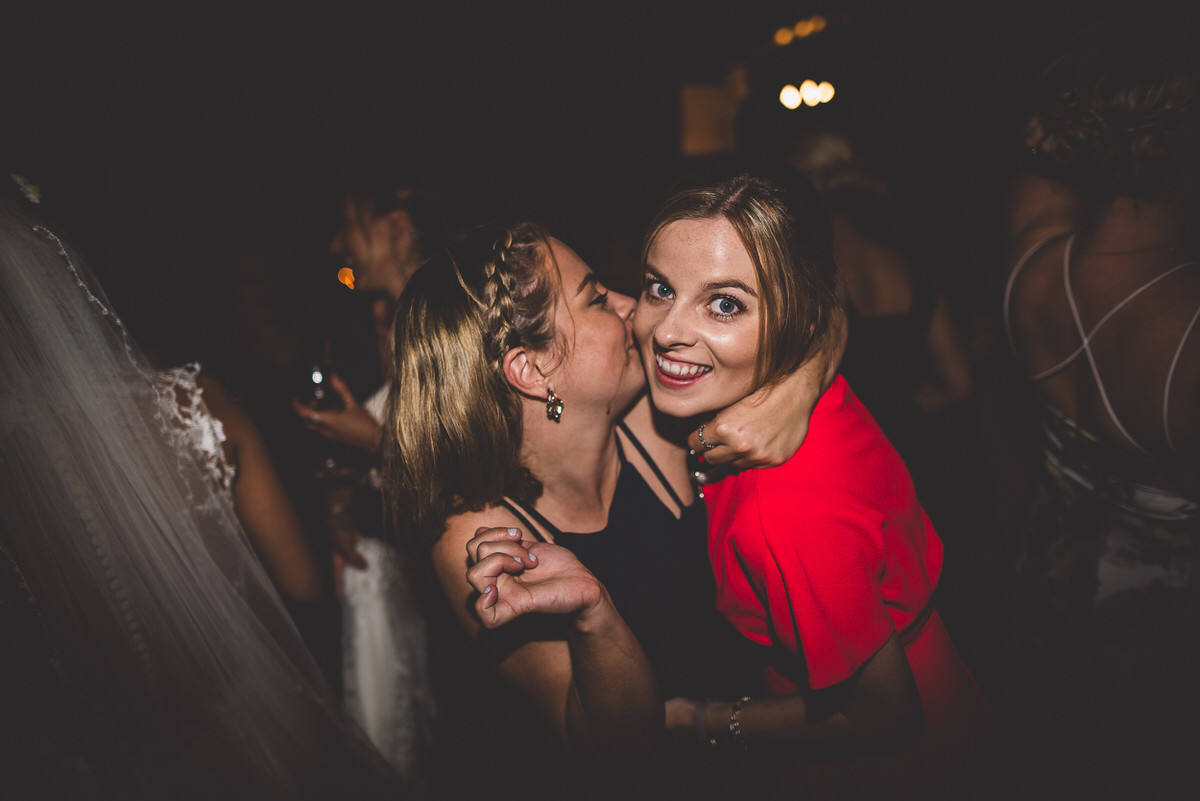 Two brides hugging on the dance floor at a wedding, captured in a beautiful wedding photo.