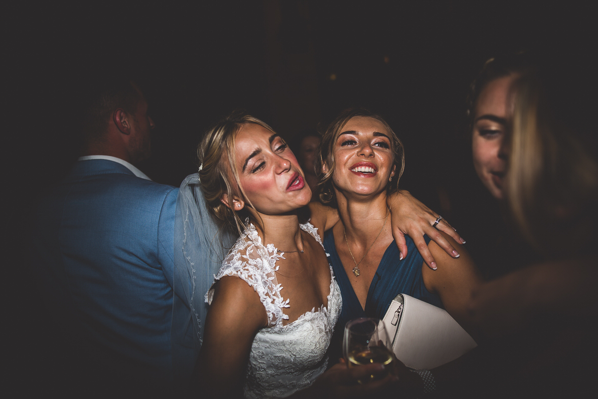 A wedding photographer captures two brides dancing at a wedding reception.