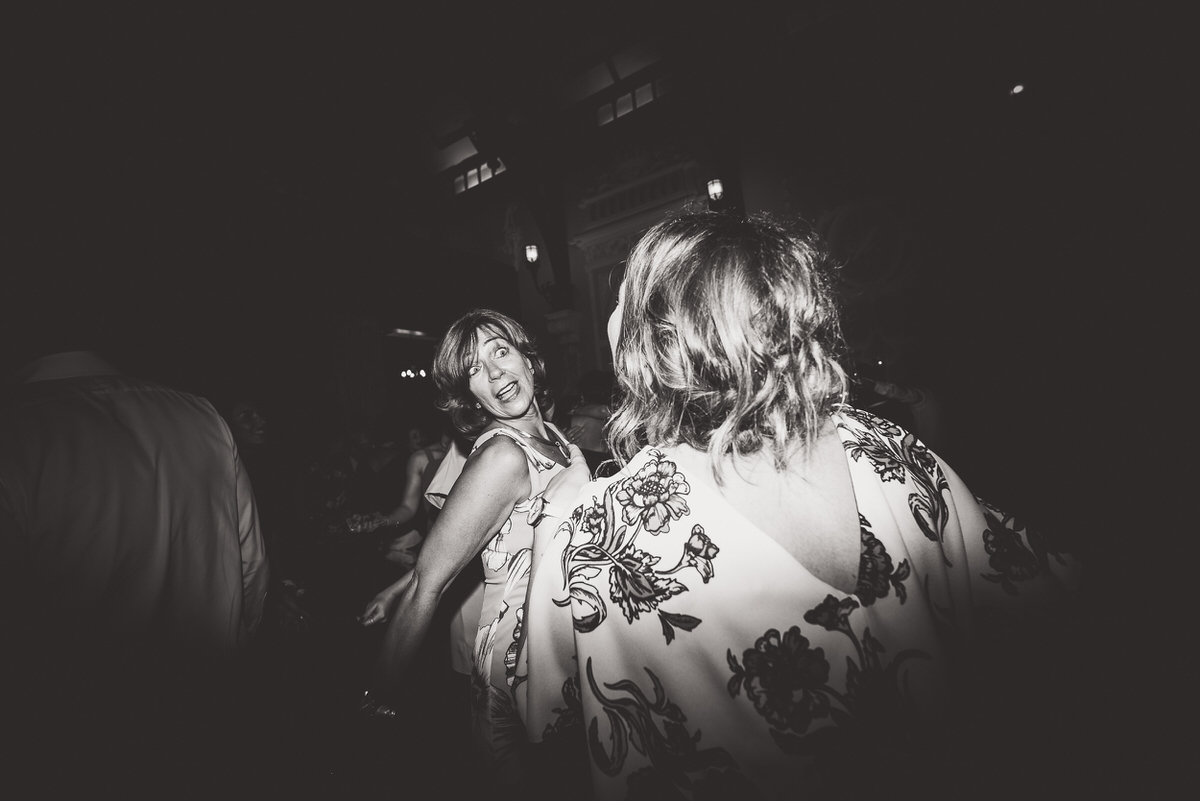 A black and white photo capturing two women dancing at a wedding party.