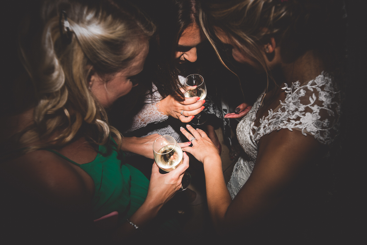 A group of bridesmaids posing for the wedding photographer with champagne in a dark room.