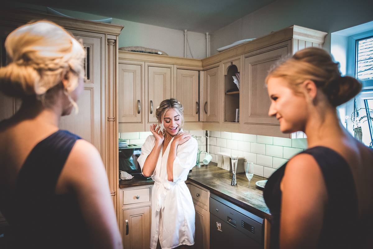 Two bridesmaids admiring each other's dresses in the mirror, captured by the wedding photographer.