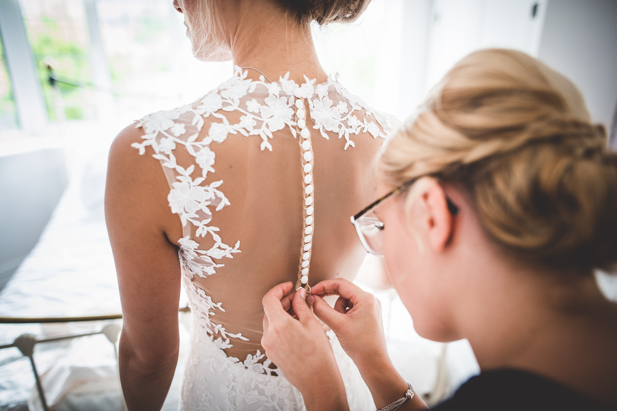 A bride is putting on her wedding dress for a wedding photo.