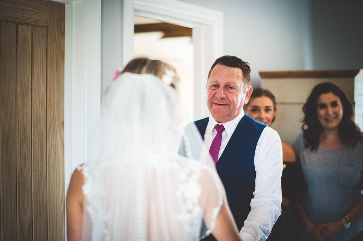 A bride, accompanied by her father, walks down the aisle at her wedding.