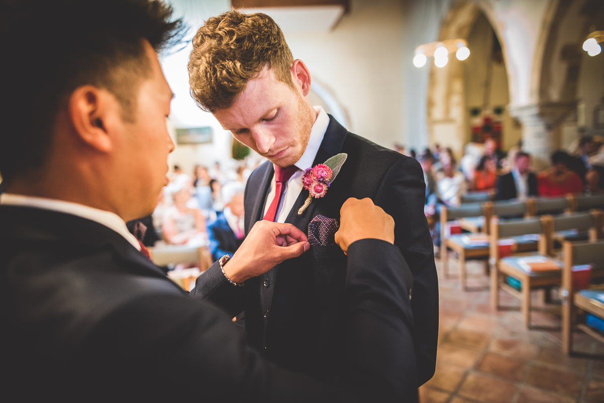 A man adjusts a boutonniere at a wedding ceremony.