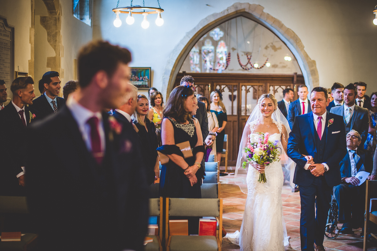A bride and groom captured in a beautiful wedding photo as they walk down the aisle in a church.