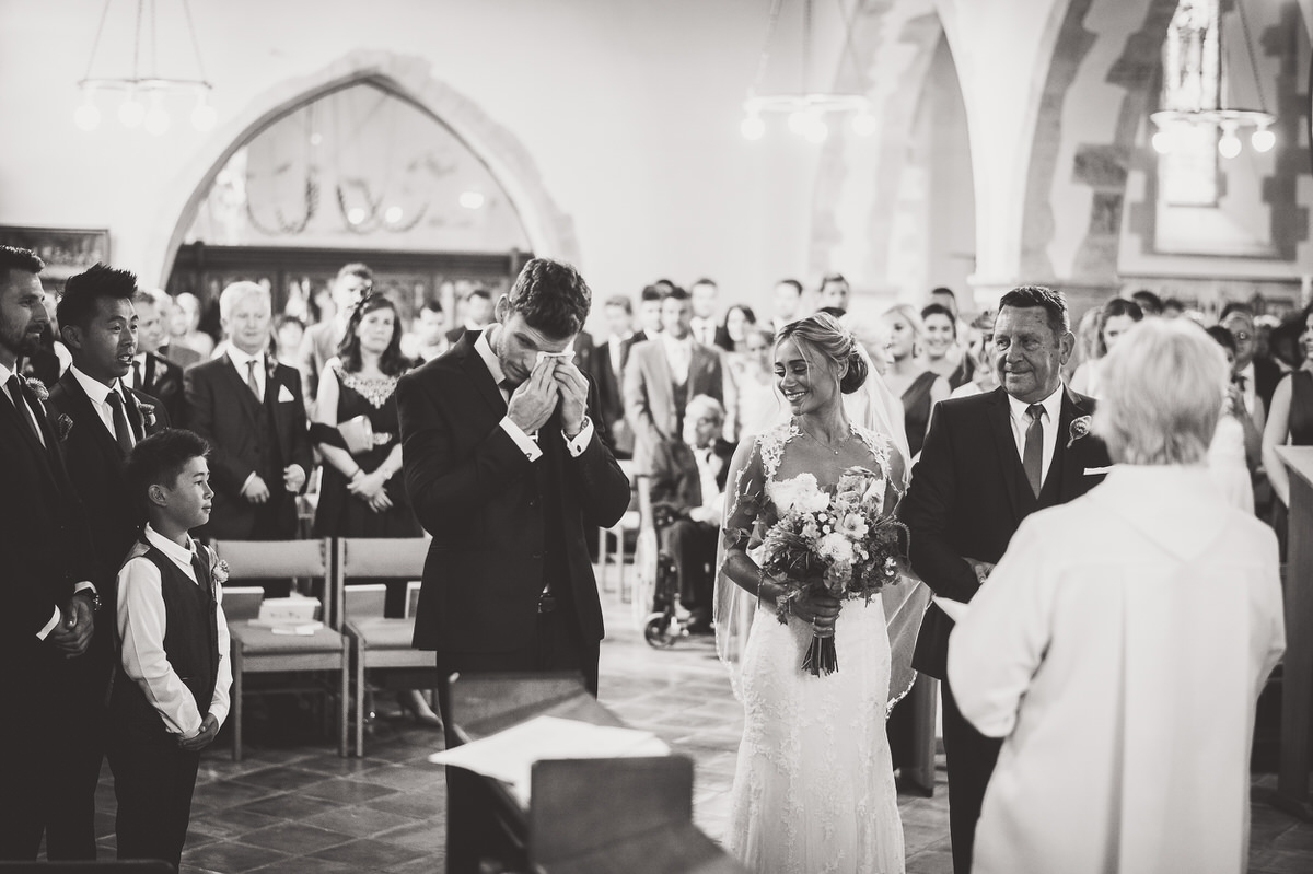 A bride and groom photographed during their wedding ceremony in a church.