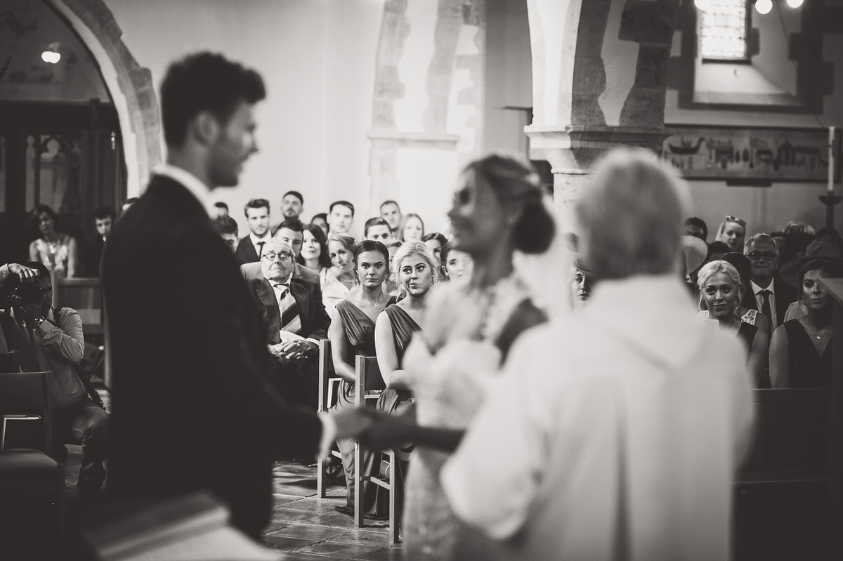 A wedding photographer captures the moment as a bride and groom exchange vows in a church.