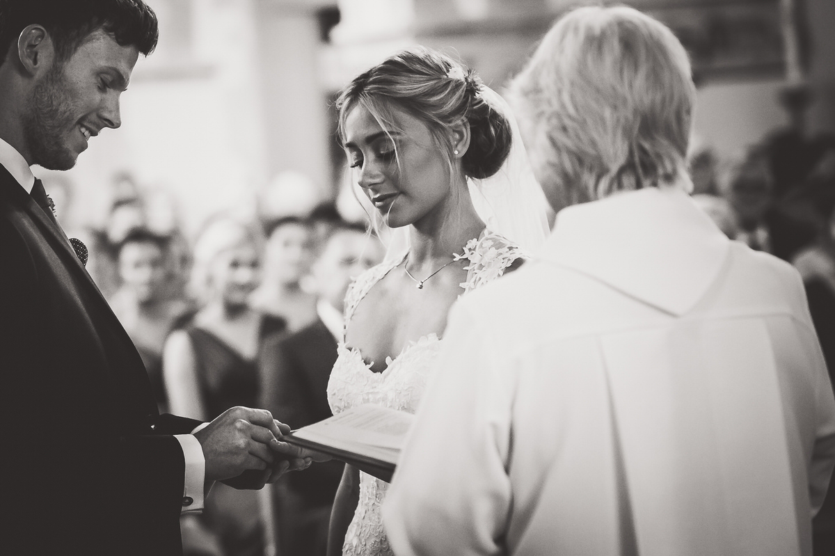 A wedding photographer capturing a bride and groom exchanging their vows in a church.