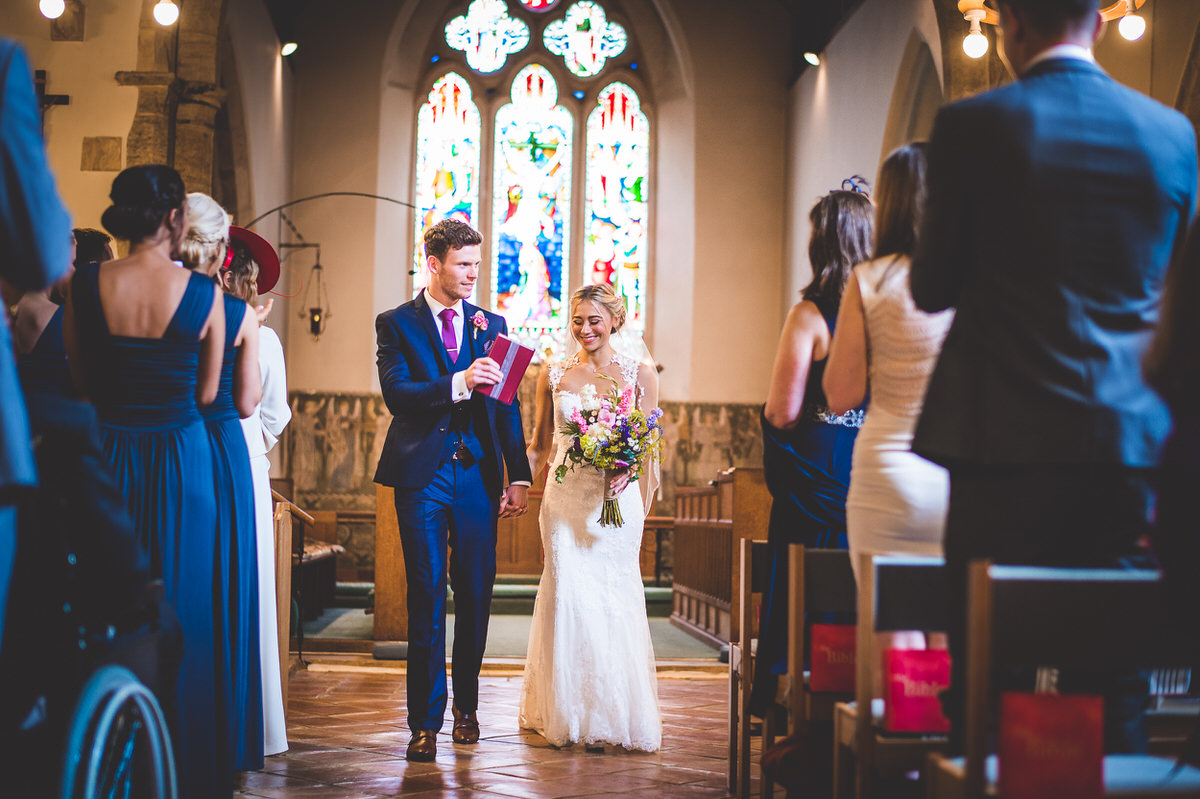 A bride and groom beautifully captured in a wedding photo as they walk down the aisle of a church.