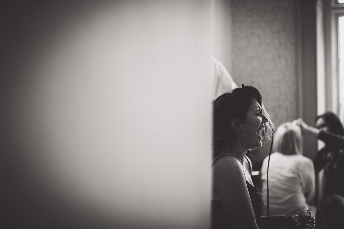 Black and white wedding photo of a bride getting ready in a room.