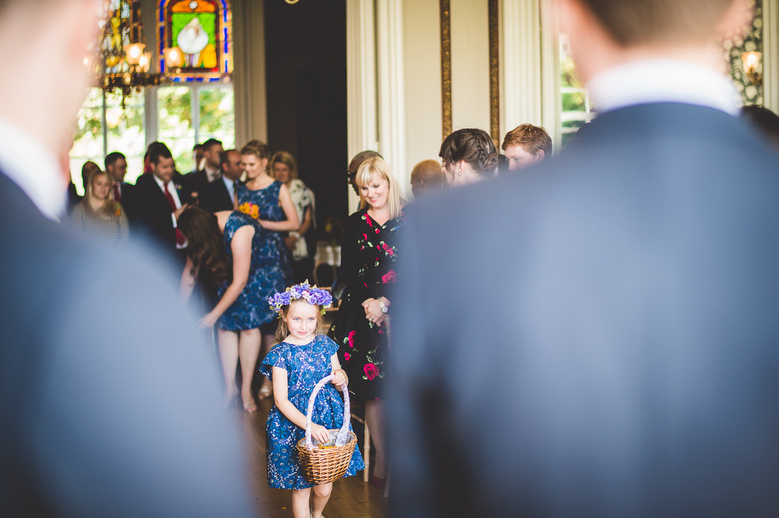 A little girl is walking down the aisle as a member of the wedding party.