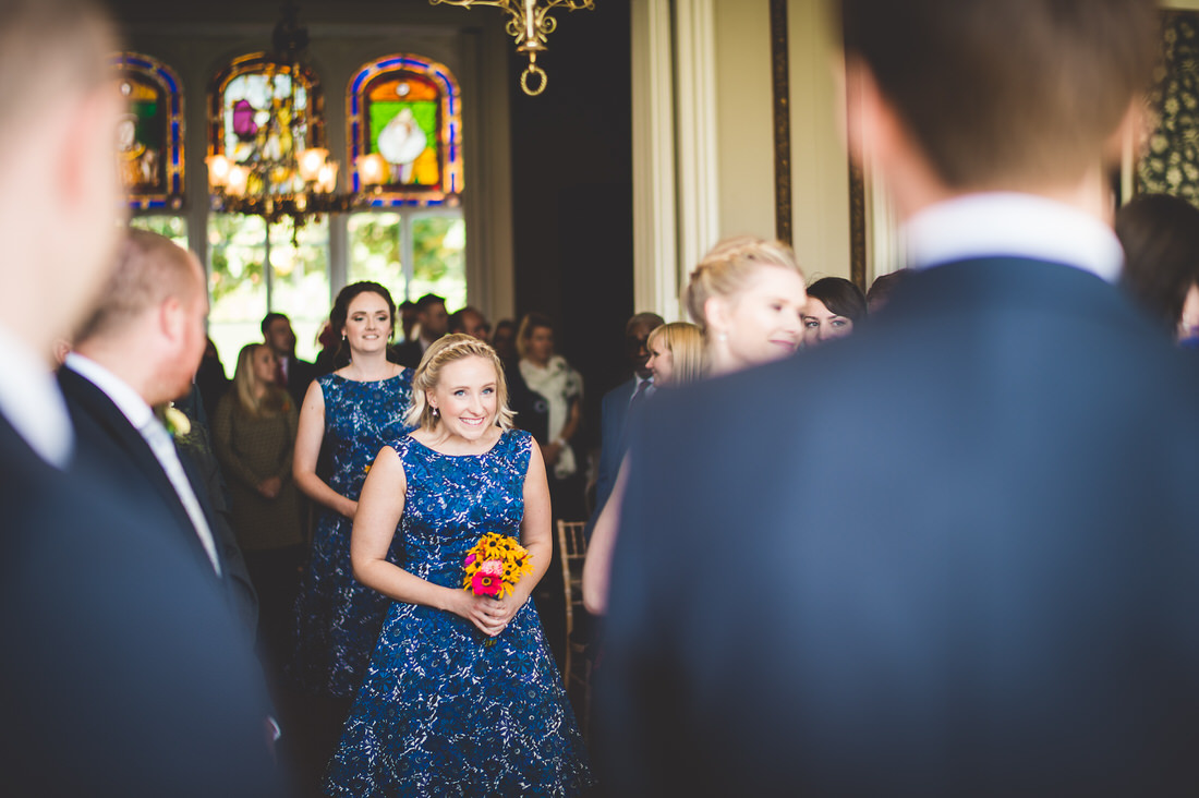 A bride and her bridesmaids walk down the aisle, captured by the wedding photographer for a memorable wedding photo.